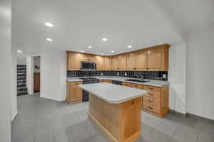 Kitchen featuring black appliances, sink, light countertops, and recessed lighting