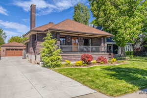 View of front of property with covered porch, front yard and a 4 car garage.