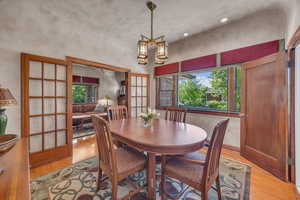 Dining room with light wood floors, healthy amount of natural light, and a chandelier