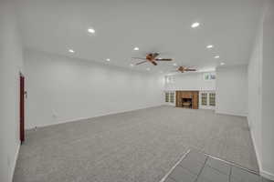Unfurnished living room featuring recessed lighting, a ceiling fan, carpet flooring, and a fireplace