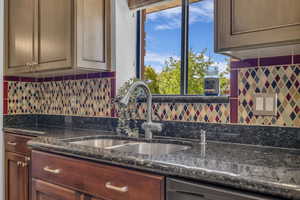 Kitchen featuring a sink, tasteful backsplash, and dark granite counters