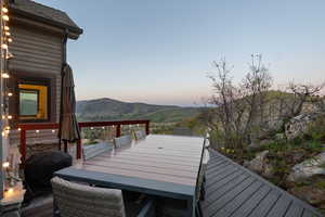 Wooden deck featuring a grill, outdoor dining area, and a mountain view
