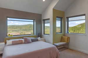 Bedroom featuring vaulted ceiling, carpet floors, and a mountain view