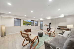 Living area with a wood stove, light wood-style flooring, baseboards, and recessed lighting