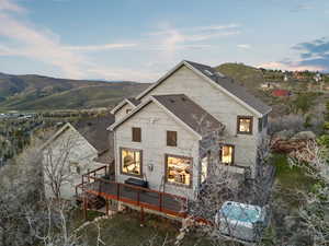 Back of property with a deck with mountain view and roof with shingles