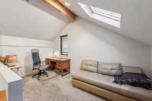 Home office with baseboards, carpet flooring, and vaulted ceiling with skylight