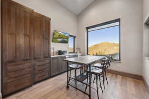 Dining room with high vaulted ceiling, baseboards, and light wood-type flooring