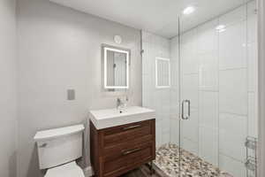Bathroom featuring vanity, toilet, and a shower stall