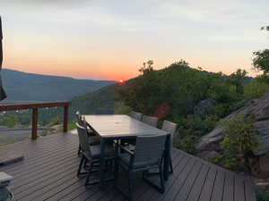 Deck at dusk featuring outdoor dining area and a mountain view