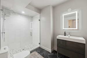 Full bathroom featuring a shower stall, marble finish floors, toilet, vanity, and baseboards
