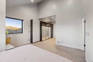 Bedroom featuring light colored carpet, a towering ceiling, visible vents, recessed lighting, and baseboards