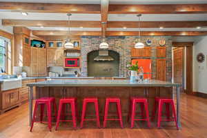 Kitchen with white microwave, light wood-style flooring, a sink, and brown cabinets