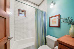 Bathroom featuring toilet and shower / bathtub combination with curtain