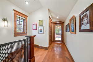 Hallway with lofted ceiling, recessed lighting, baseboards, light wood finished floors, and visible vents