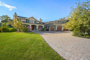 View of front of property with decorative driveway, a chimney, and a front yard