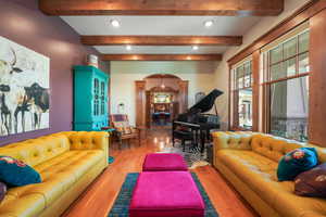 Living room with recessed lighting, decorative columns, arched walkways, and wood finished floors