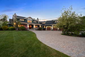 View of front of home featuring a porch, a garage, a chimney, decorative driveway, and a lawn