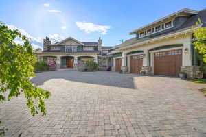 View of front of home featuring stone siding, a garage, and decorative driveway
