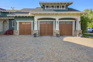 View of front of home with a garage, decorative driveway, and stone siding