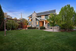 Back of property featuring stone siding, a playground, a chimney, and a lawn