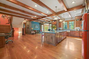 Kitchen featuring a breakfast bar, stainless steel counters, brown cabinetry, open floor plan, and light wood-type flooring