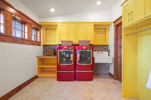 Laundry room featuring washer and clothes dryer, cabinet space, a sink, and baseboards