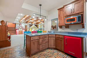 Kitchen with a peninsula, brick floor, brown cabinets, and a sink
