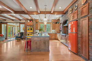 Kitchen with fridge, a barn door, an island with sink, light wood finished floors, and open floor plan