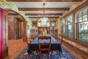 Dining space featuring light wood-style flooring, visible vents, a chandelier, arched walkways, and beam ceiling