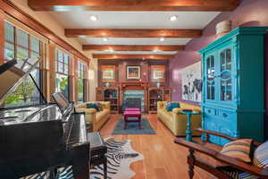 Living area with light wood finished floors, beamed ceiling, a high end fireplace, and recessed lighting