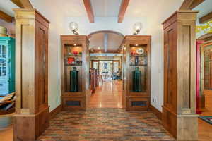 Hallway with brick floor, ornate columns, beamed ceiling, and arched walkways