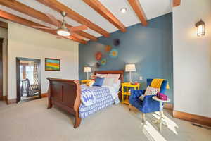 Bedroom featuring carpet flooring, baseboards, and beamed ceiling