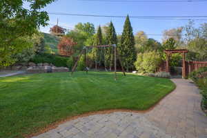View of yard featuring a fenced backyard, a pergola, and a playground