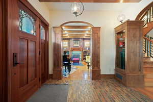 Foyer featuring brick floor, arched walkways, stairway, a fireplace, and ornate columns