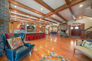 Living area featuring beam ceiling, light wood-type flooring, ornate columns, recessed lighting, and arched walkways