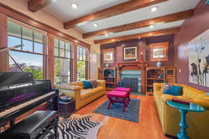Living room featuring recessed lighting, wood finished floors, beamed ceiling, and a high end fireplace