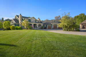 View of front of house with stone siding, a chimney, and a front yard