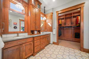Bathroom with double vanity, baseboards, a walk in closet, and a sink