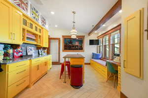 Kitchen with a kitchen breakfast bar, visible vents, a center island, glass insert cabinets, and baseboards