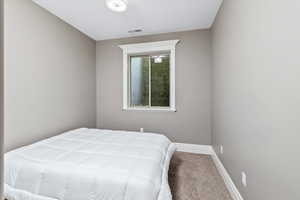 Carpeted bedroom featuring baseboards and visible vents