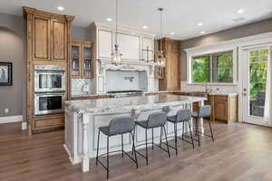 Kitchen featuring brown cabinets, a center island, light wood-type flooring, and stainless steel double oven