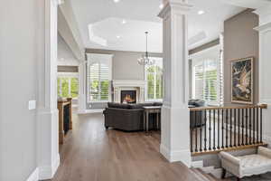 Living room featuring plenty of natural light, baseboards, decorative columns, and hardwood / wood-style floors