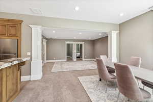 Dining space featuring light carpet, recessed lighting, and ornate columns