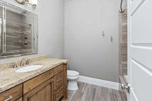 Bathroom with vanity, toilet, baseboards, and tiled shower