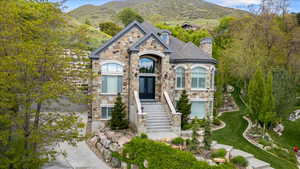 View of front of house with a mountain view, a chimney, french doors, and stone siding