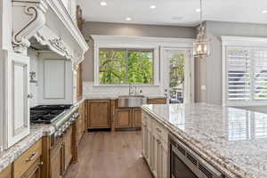 Kitchen featuring light wood-style flooring, a sink, brown cabinetry, plenty of natural light, and appliances with stainless steel finishes