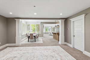Dining room featuring light carpet, baseboards, and decorative columns