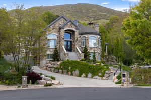 French country home featuring a chimney, french doors, a mountain view, stairs, and stone siding
