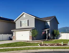 Traditional home featuring fence, an attached garage, stucco siding, concrete driveway, and a front lawn