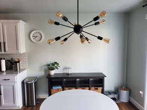 Interior space with dark wood-style flooring, baseboards, and an inviting chandelier